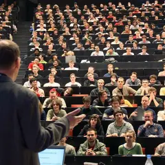 Dozenten sprechen vor vielen Studenten in einem Hörsaal. Einer von ihnen ist ein Bachelor-Ingenieur, der hier lernt.