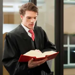 Ein junger Mann im Talar studiert ein dickes Buch. Er bereitet sich auf sein Referendariat in Hamburg für das Lehramt vor.