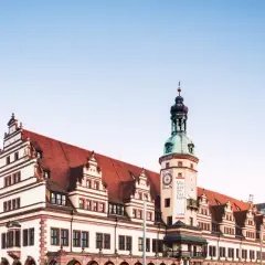 Altes Rathaus mit Turm und moderner Architektur in Leipzig. Die Fassade des Rathauses ist mit roten Ziegeln und weißen Verzierungen geschmückt.