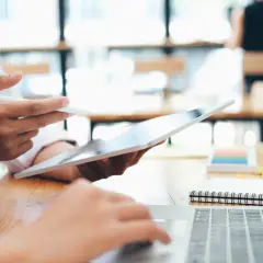Zwei Personen arbeiten an einem Laptop und Tablet. Sie studieren für ihren **bachelor in business administration**.