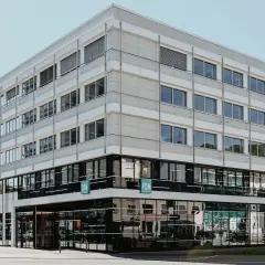 Modernes Gebäude der FOM Hochschule in Wuppertal. Helle Fassade mit vielen Fenstern, unten dunkle Glasfront.