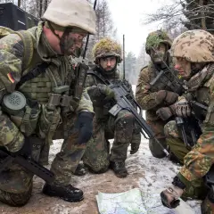 Vier Soldaten der Bundeswehr besprechen im verschneiten Wald eine Karte.