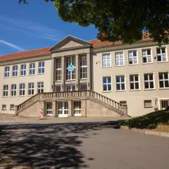 Das Gebäude der Nordhausen University mit einer breiten Steintreppe und vielen Fenstern unter einem blauen Himmel.