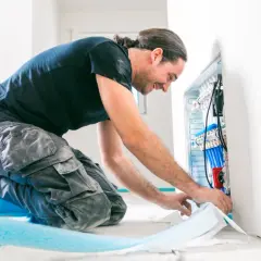 Ein Anlagenmechaniker bei der Arbeit an einem Heizungsverteiler. Er fragt sich, wie viel verdient man als Anlagenmechaniker in diesem Beruf.