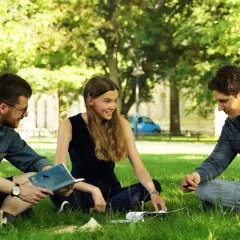 Drei Studierende diskutieren im Grünen über Umweltethik an der Uni Augsburg.
