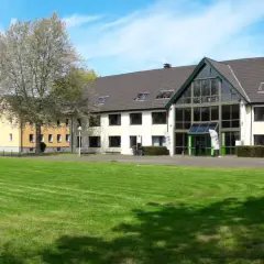 Grüne Rasenflächen und Gebäude der uni unna im Sonnenschein.