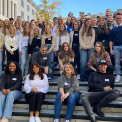Eine Gruppe junger Leute posiert lächelnd vor einem Gebäude der HS Fresenius Hamburg.