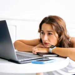 Junge Frau blickt nachdenklich auf ihren Laptop. Nach dem Studium ist die Jobsuche zermürbend.