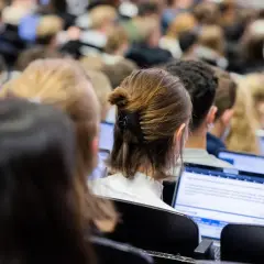 Studenten in einem Hörsaal, die auf Laptops schauen. Die Frage, wie lange dauert ein Bachelor Studium, beschäftigt viele von ihnen.