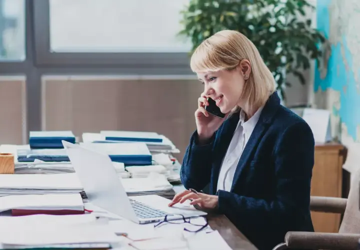 Eine Frau am Telefon und Laptop, die sich mit dem Steuerrecht beschäftigt.