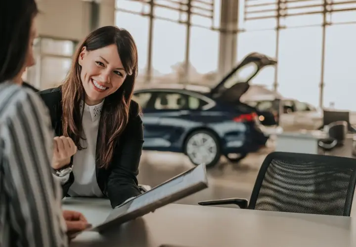 Lächelnde Automobilkauffrau erklärt Unterlagen. Die Ausbildung zur Automobilkauffrau bietet gute Perspektiven, auch beim Gehalt.