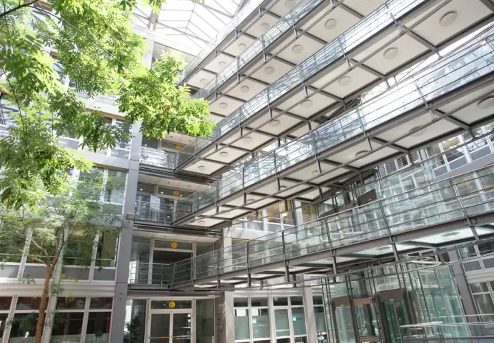 Moderne Architektur mit Glasbrücken und viel Grün im Innenhof der Hochschule Stuttgart.
