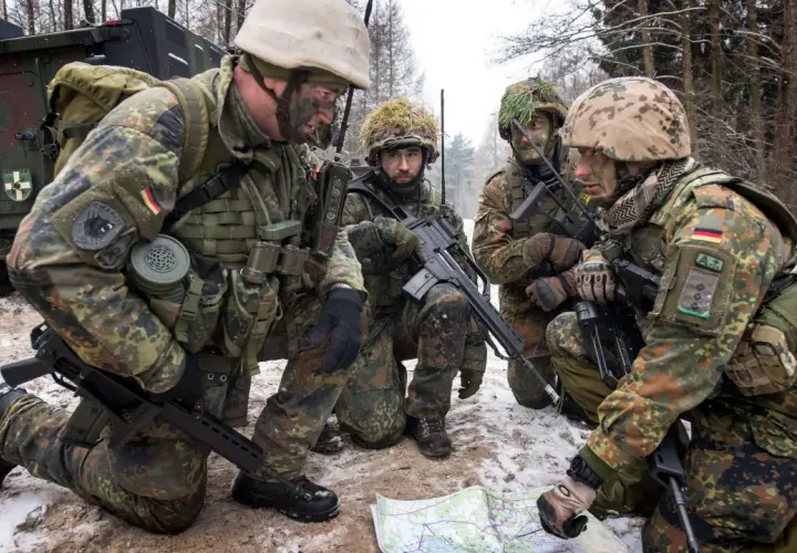 Vier Soldaten der Bundeswehr besprechen im verschneiten Wald eine Karte.