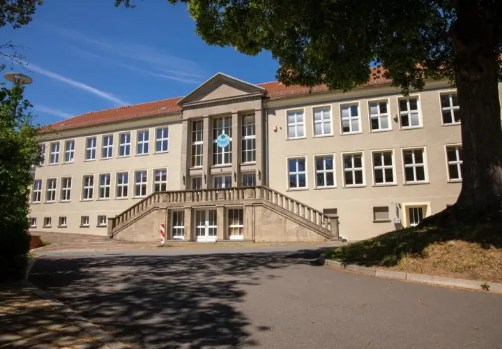 Das Gebäude der Nordhausen University mit einer breiten Steintreppe und vielen Fenstern unter einem blauen Himmel.