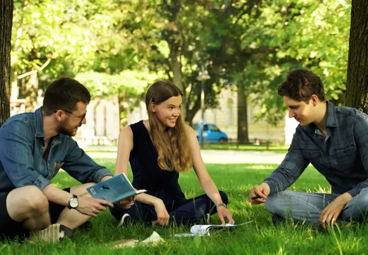 Drei Studierende diskutieren im Grünen über Umweltethik an der Uni Augsburg.