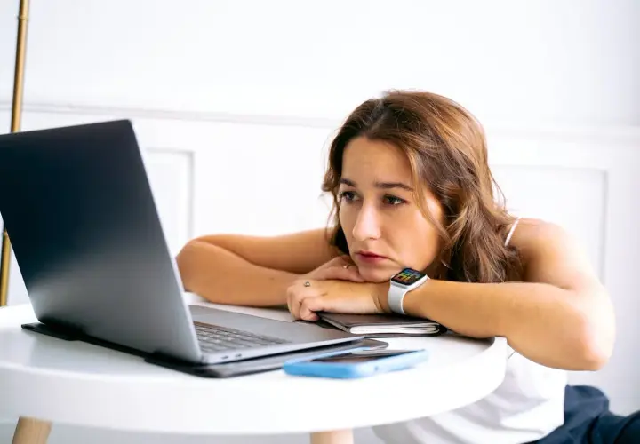 Junge Frau blickt nachdenklich auf ihren Laptop. Nach dem Studium ist die Jobsuche zermürbend.
