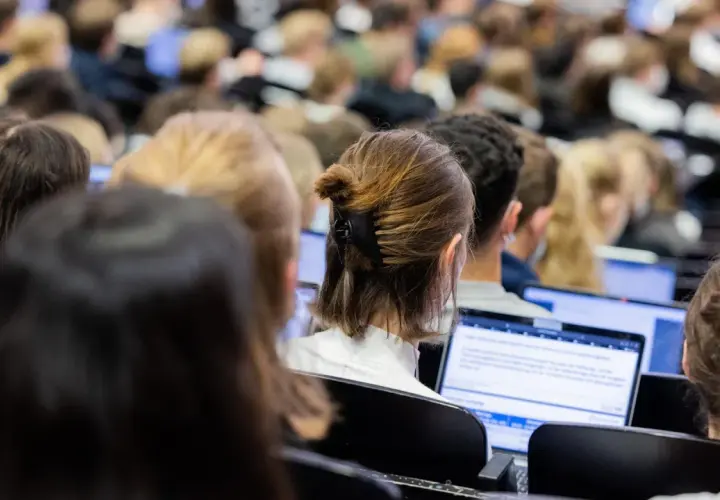 Studenten in einem Hörsaal, die auf Laptops schauen. Die Frage, wie lange dauert ein Bachelor Studium, beschäftigt viele von ihnen.