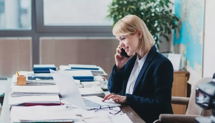 Eine Frau am Telefon und Laptop, die sich mit dem Steuerrecht beschäftigt.