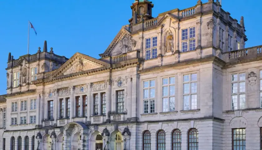 Prachtvolles Gebäude einer **Uni England** mit vielen Fenstern und architektonischen Details, beleuchtet im Abendlicht.
