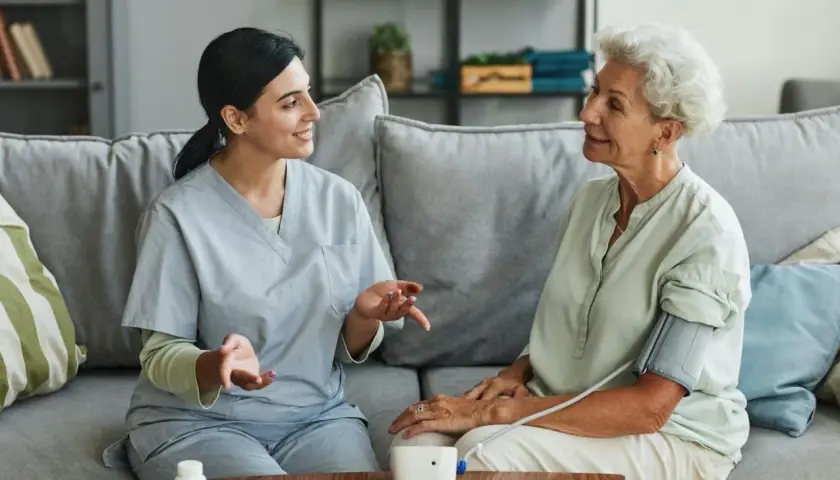 Pflegekraft misst Blutdruck bei älterer Dame. Ein Beispiel für wichtige soziale Berufe, die Menschen im Alltag unterstützen.
