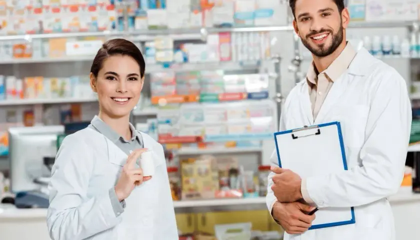 Zwei freundliche Apotheker in weißen Kitteln, die Medikamente und eine Patientenakte präsentieren. Einblick in verschiedene Berufe auf Deutsch.