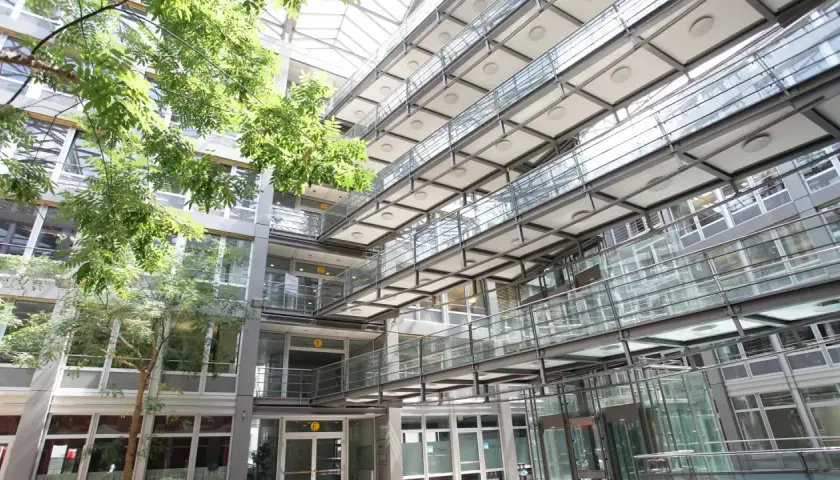 Moderne Architektur mit Glasbrücken und viel Grün im Innenhof der Hochschule Stuttgart.