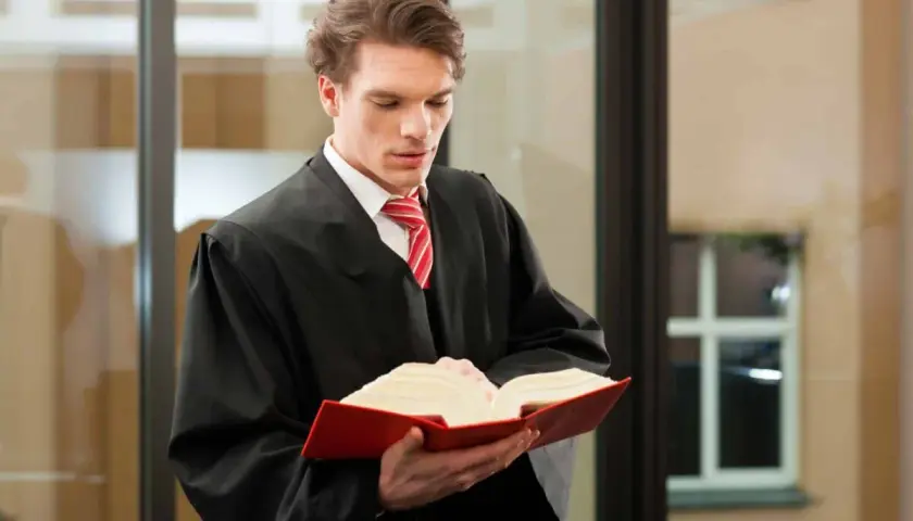 Ein junger Mann im Talar studiert ein dickes Buch. Er bereitet sich auf sein Referendariat in Hamburg für das Lehramt vor.