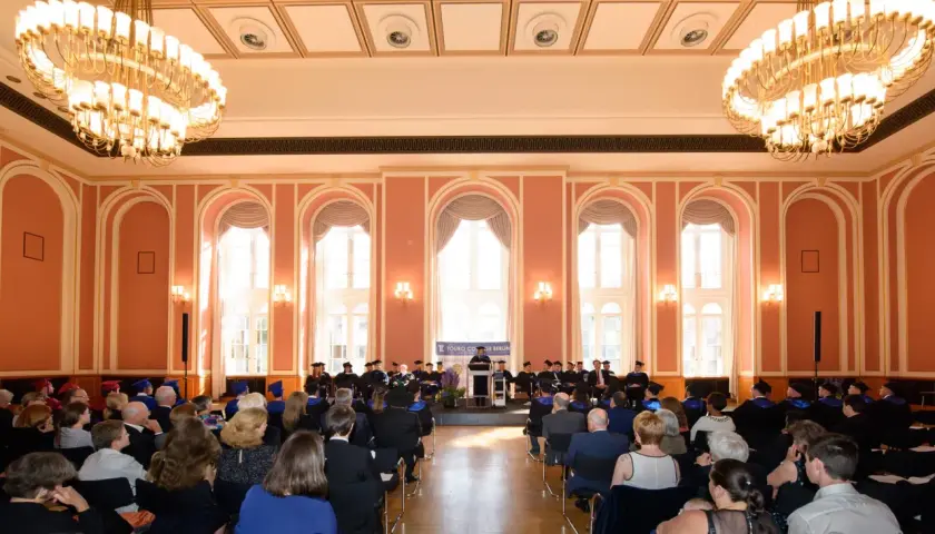 Absolventen der Touro University Berlin feiern ihren Abschluss in einem prunkvollen Saal mit Kronleuchtern.