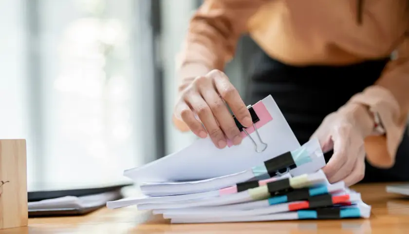 Hände sortieren Dokumente. Die Ausbildung zum Justizfachwirt und das Gehalt sind wichtige Aspekte für angehende Juristen.