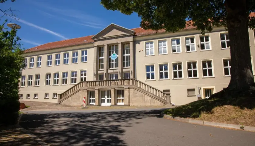 Das Gebäude der Nordhausen University mit einer breiten Steintreppe und vielen Fenstern unter einem blauen Himmel.