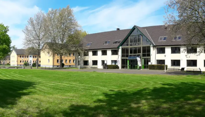 Grüne Rasenflächen und Gebäude der uni unna im Sonnenschein.