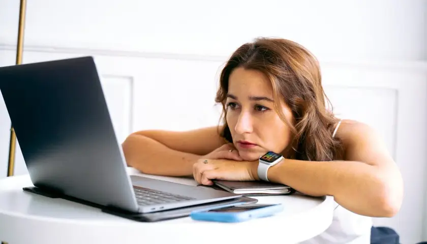 Junge Frau blickt nachdenklich auf ihren Laptop. Nach dem Studium ist die Jobsuche zermürbend.