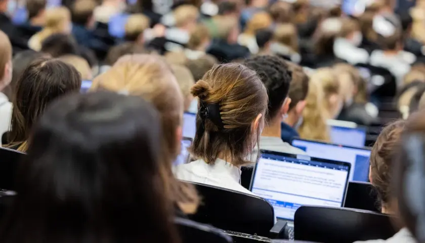 Studenten in einem Hörsaal, die auf Laptops schauen. Die Frage, wie lange dauert ein Bachelor Studium, beschäftigt viele von ihnen.
