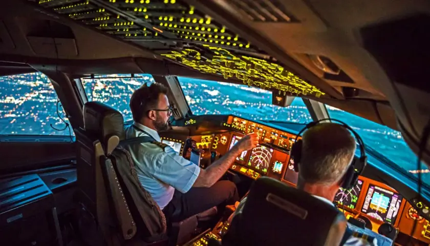 Zwei Piloten im Cockpit bei Nachtflug. Die Frage, wie viel verdient ein Pilot im Monat, beschäftigt viele.