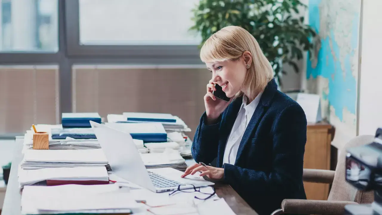 Eine Frau am Telefon und Laptop, die sich mit dem Steuerrecht beschäftigt.