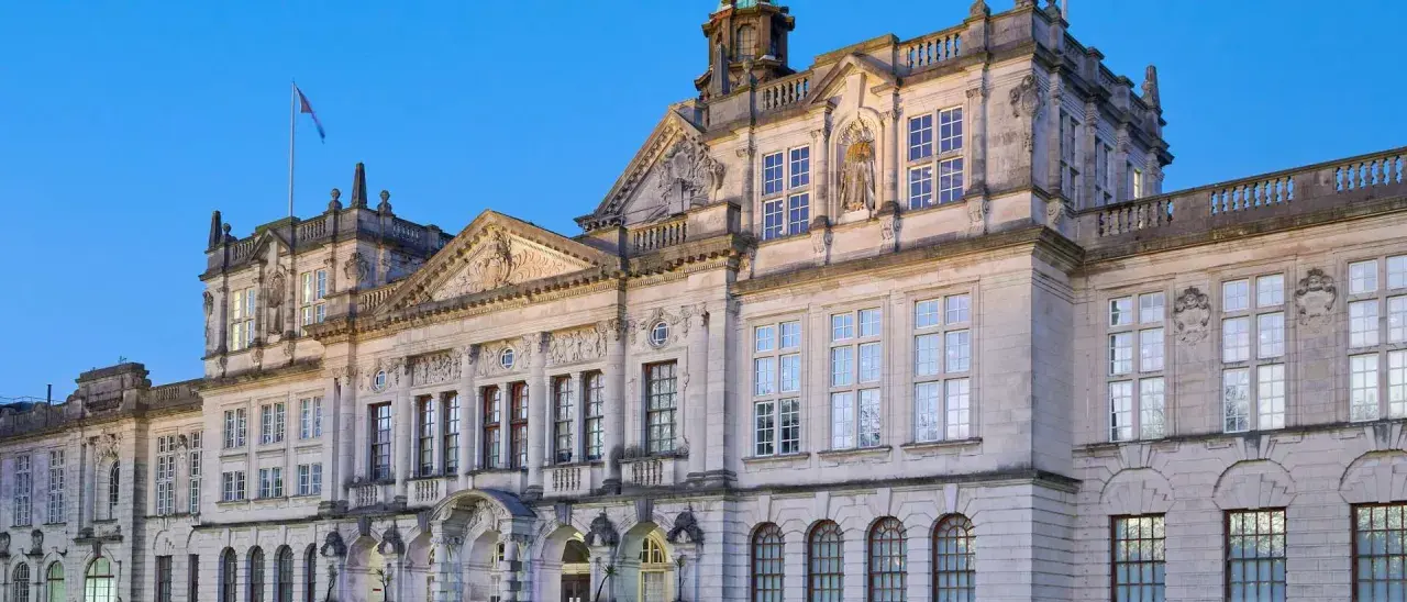 Prachtvolles Gebäude einer **Uni England** mit vielen Fenstern und architektonischen Details, beleuchtet im Abendlicht.
