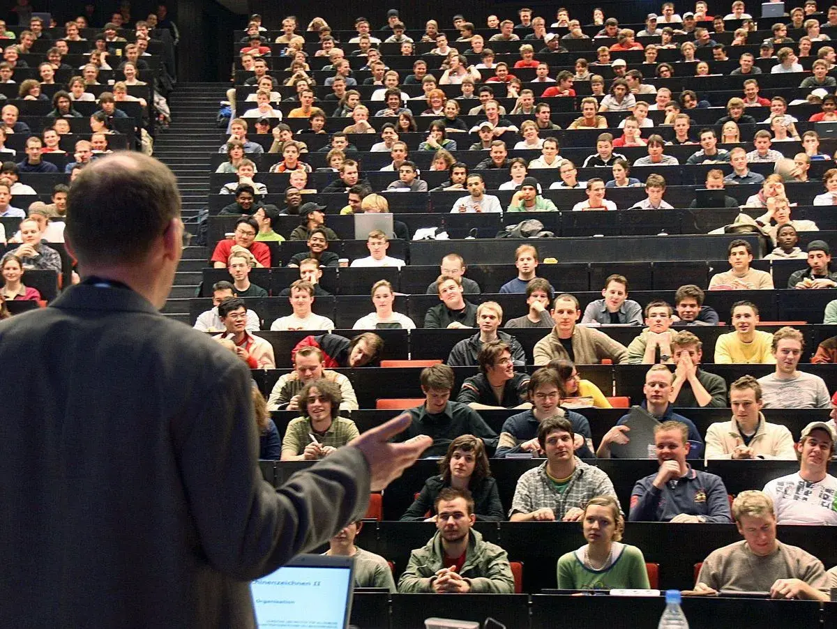 Dozenten sprechen vor vielen Studenten in einem Hörsaal. Einer von ihnen ist ein Bachelor-Ingenieur, der hier lernt.