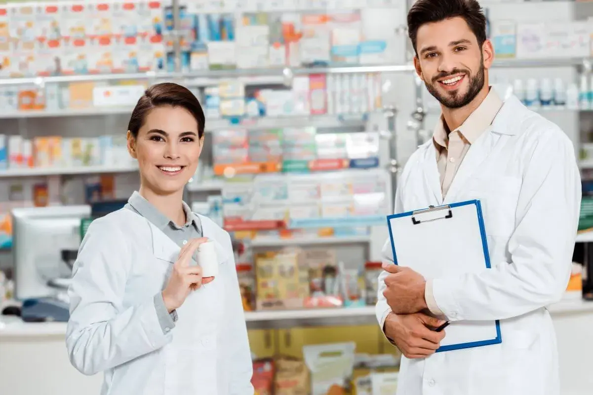 Zwei freundliche Apotheker in weißen Kitteln, die Medikamente und eine Patientenakte präsentieren. Einblick in verschiedene Berufe auf Deutsch.