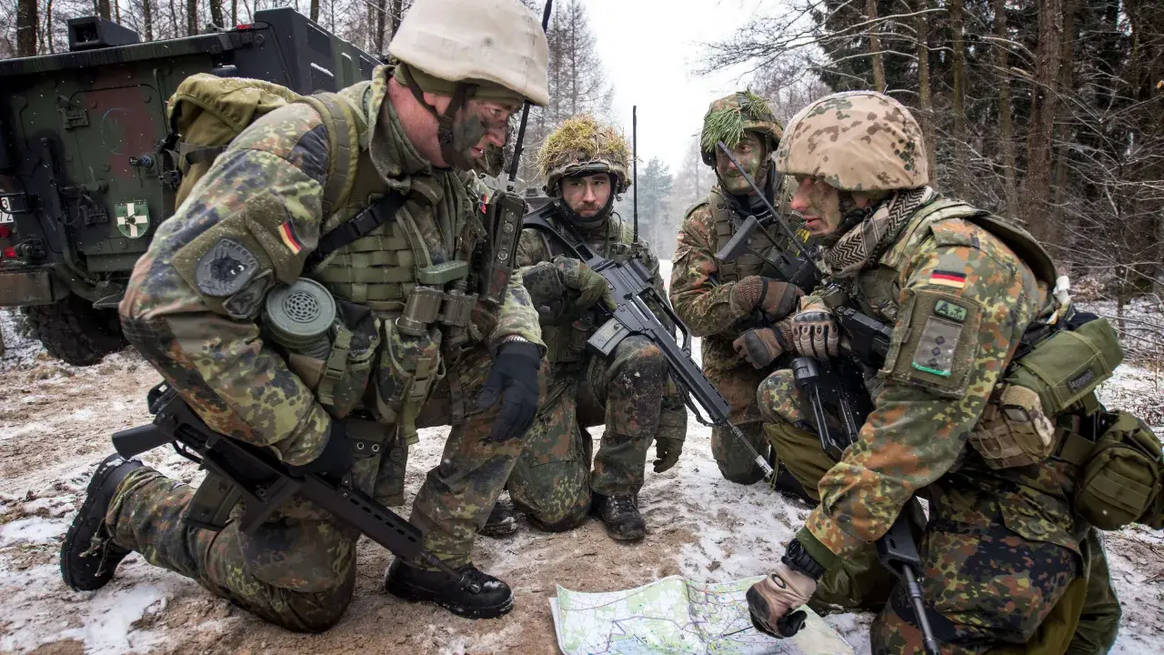 Vier Soldaten der Bundeswehr besprechen im verschneiten Wald eine Karte.