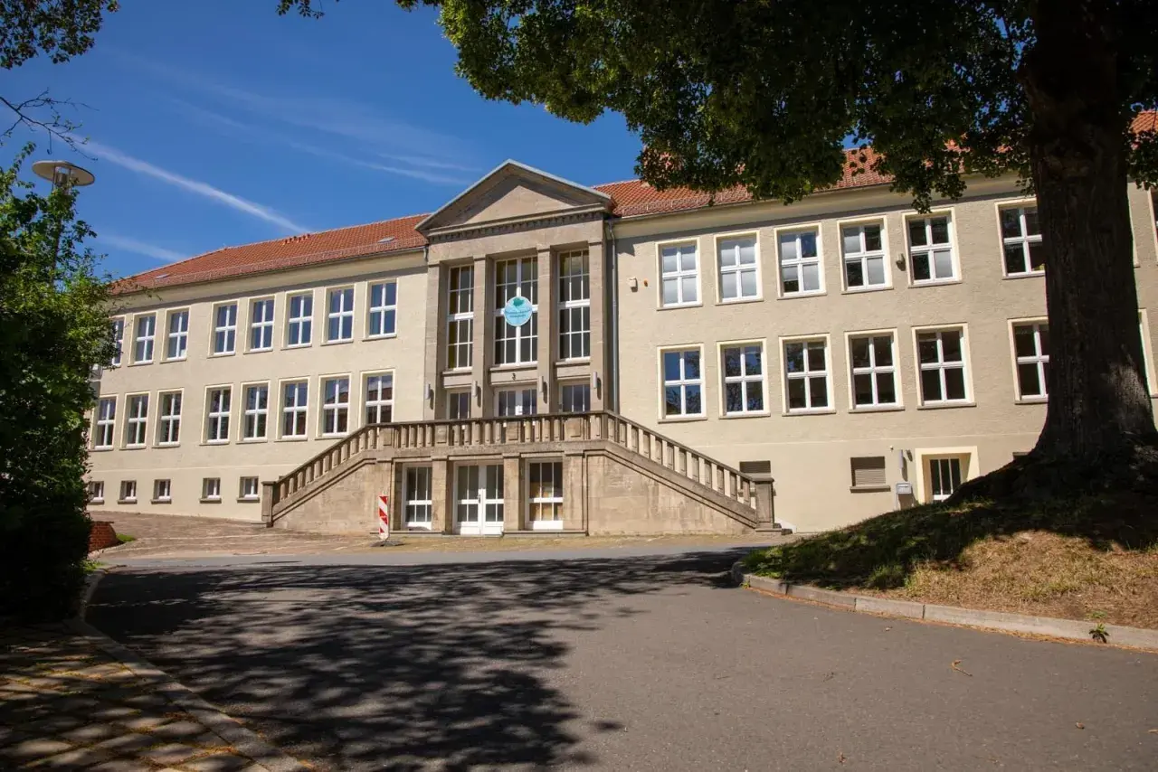 Das Gebäude der Nordhausen University mit einer breiten Steintreppe und vielen Fenstern unter einem blauen Himmel.