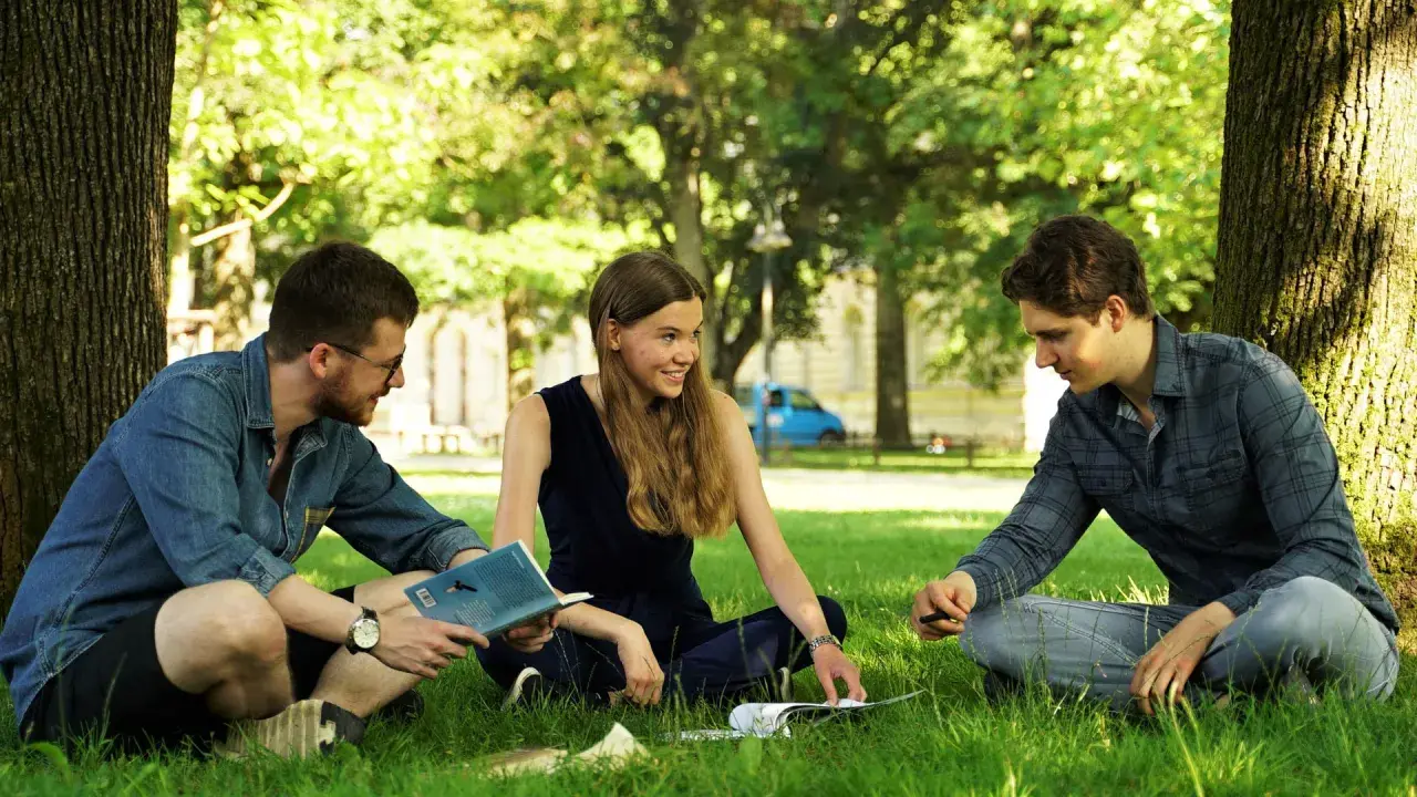 Drei Studierende diskutieren im Grünen über Umweltethik an der Uni Augsburg.