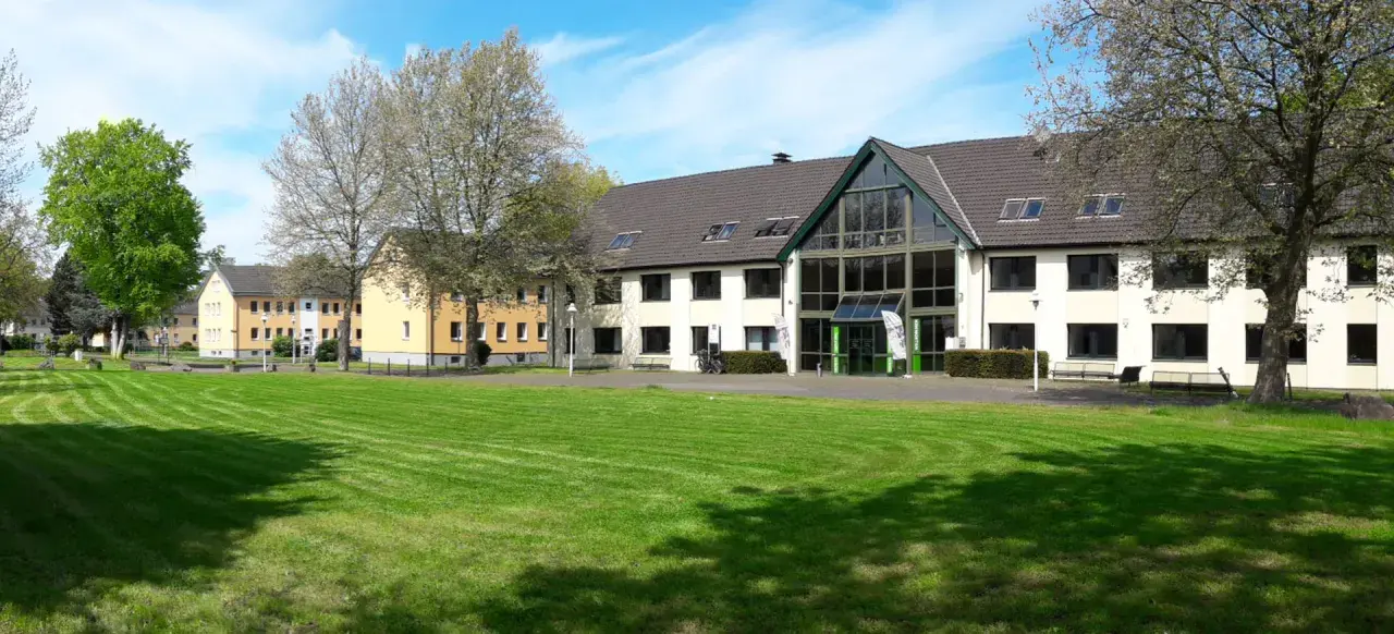 Grüne Rasenflächen und Gebäude der uni unna im Sonnenschein.