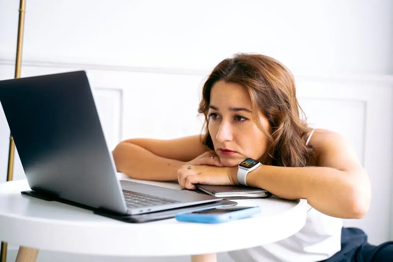 Junge Frau blickt nachdenklich auf ihren Laptop. Nach dem Studium ist die Jobsuche zermürbend.