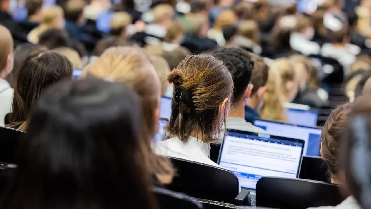 Studenten in einem Hörsaal, die auf Laptops schauen. Die Frage, wie lange dauert ein Bachelor Studium, beschäftigt viele von ihnen.