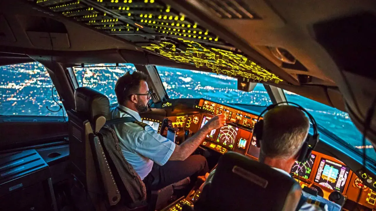 Zwei Piloten im Cockpit bei Nachtflug. Die Frage, wie viel verdient ein Pilot im Monat, beschäftigt viele.