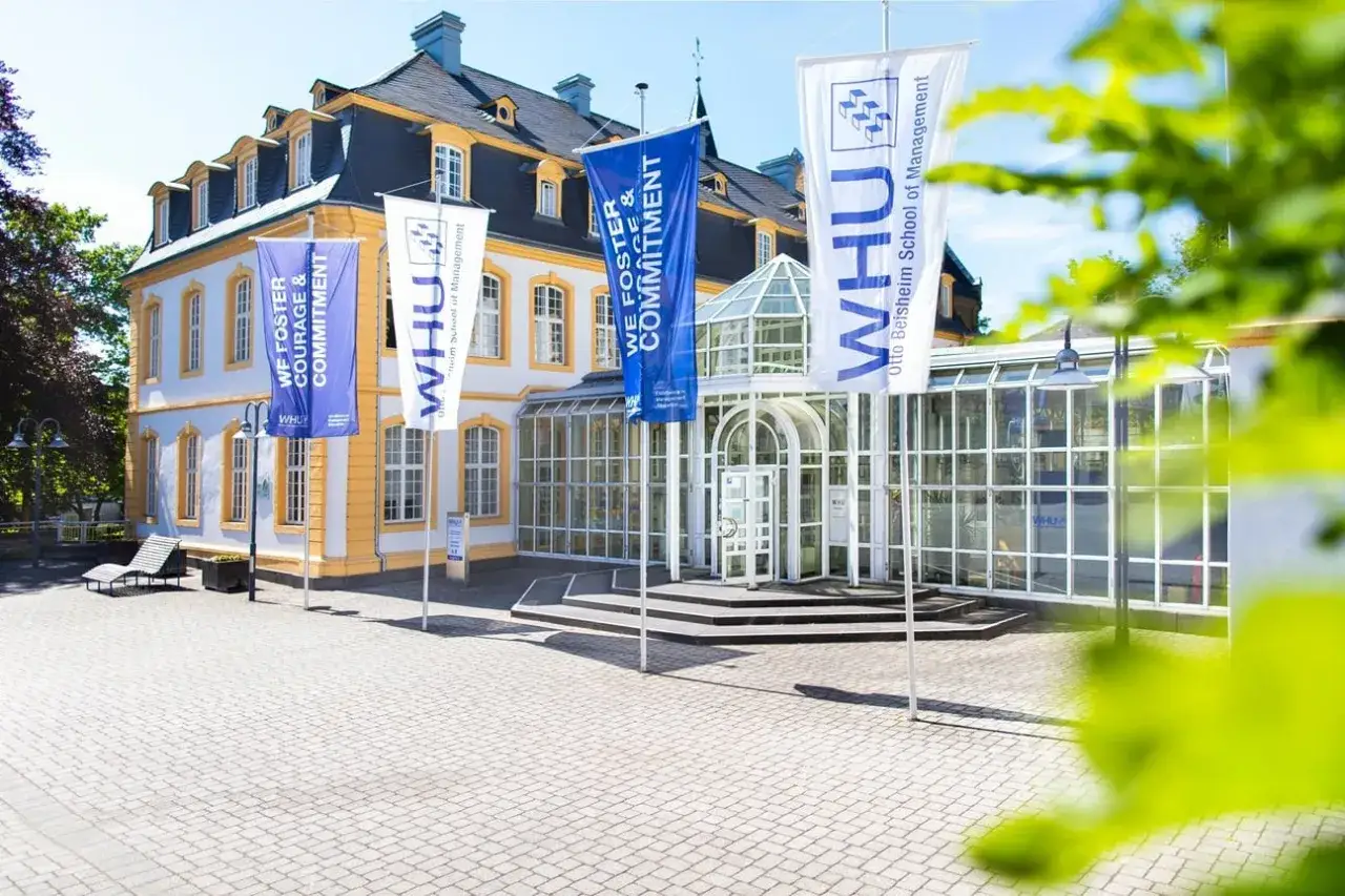 WHU Otto Beisheim School of Management: Hier beginnt Ihr Management Studium. Fahnen wehen vor dem Gebäude.