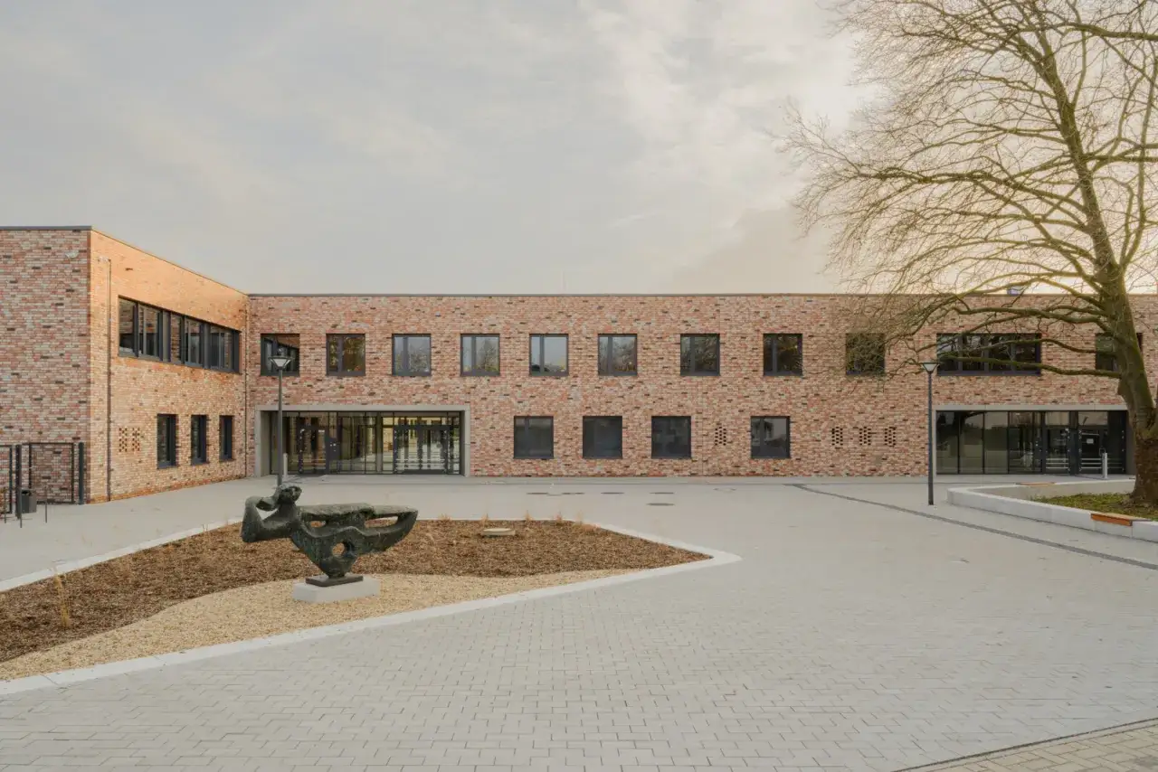 Moderne Backsteingeb&auml;ude der uni unna mit Skulptur im Hof.