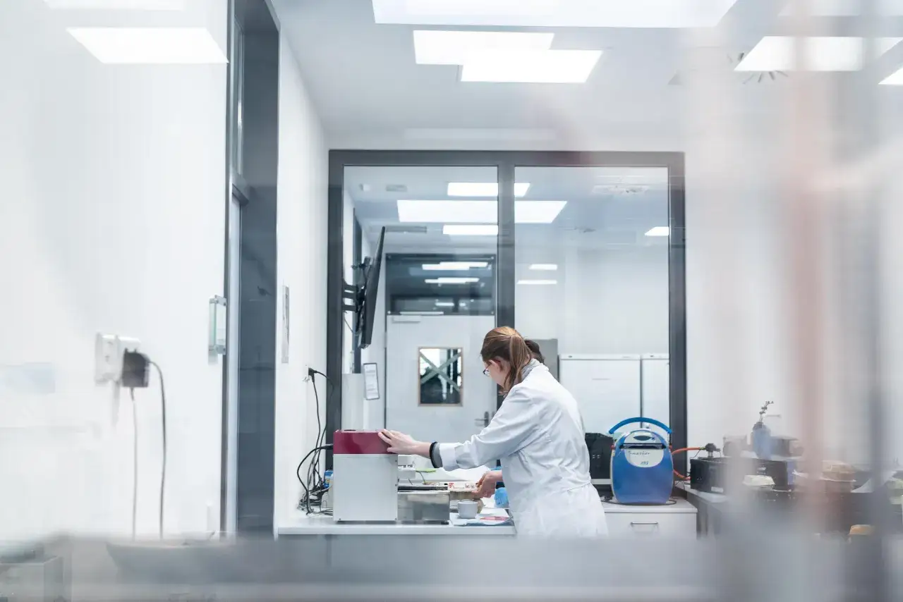 Frau im weißen Kittel arbeitet im Labor an Geräten, ein Einblick in das Oecotrophologie Studium.