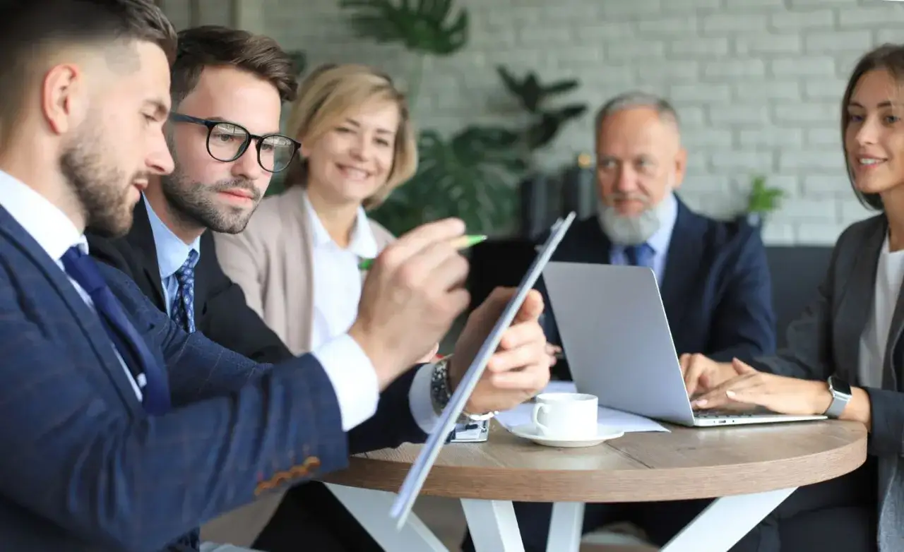 Geschäftsprofis besprechen Strategien. Einer hält ein Dokument, das auf einen Bachelor of Arts in Business Administration hindeutet.