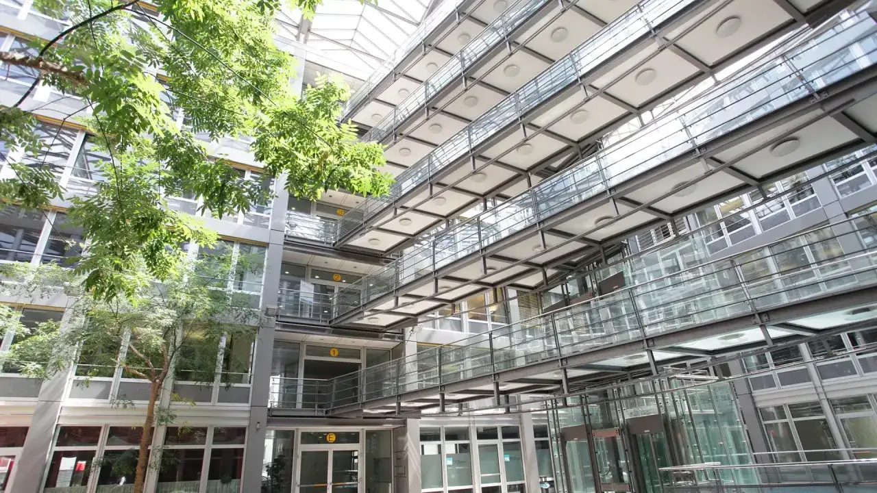 Moderne Architektur mit Glasbrücken und viel Grün im Innenhof der Hochschule Stuttgart.